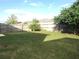 Fenced backyard with a lush green lawn, trees, and sunny sky at 10513 Leader Ln, Orlando, FL 32825
