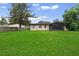 Large, grassy backyard featuring mature trees and a screened-in porch at 108 Devon Ct, Longwood, FL 32779