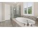Elegant bathroom featuring a large soaking tub with tile surround, glass shower, and plantation shutters at 1113 Fieldstone Cir, Oviedo, FL 32765