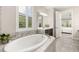 Main bathroom featuring a soaking tub, decorative tile accents, and a bright window with window shutters at 1113 Fieldstone Cir, Oviedo, FL 32765