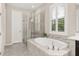 The main bathroom features a glass enclosed shower, a soaking tub, and a shuttered window at 1113 Fieldstone Cir, Oviedo, FL 32765