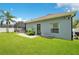 Well-maintained backyard with lush green grass and exterior house view featuring a door, window, and landscaping at 14306 Paradise Tree Dr, Orlando, FL 32828
