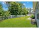 Lush green backyard with a well-maintained lawn, framed by a classic white picket fence and mature trees at 14306 Paradise Tree Dr, Orlando, FL 32828