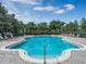 Large community pool with surrounding lounge chairs, lush landscaping and a clear blue sky at 14306 Paradise Tree Dr, Orlando, FL 32828