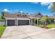 Beautiful one-story home featuring a three-car garage, well-maintained lawn, palm trees, and a gray exterior at 14306 Paradise Tree Dr, Orlando, FL 32828