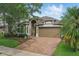 Well-maintained two-story home with a manicured lawn, brick driveway, mature trees and a two-car garage at 15038 Masthead Landing Cir, Winter Garden, FL 34787