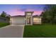 Beautiful twilight view of a cozy single-story home with manicured lawn and stylish exterior lighting at 16357 Se 88Th Ct, Summerfield, FL 34491