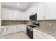 Close-up showcasing kitchen with white cabinets, granite counters, and stainless steel oven and microwave at 16357 Se 88Th Ct, Summerfield, FL 34491