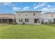 Large backyard with green grass, a covered patio, and neutral-colored two-story home at 17044 Goldcrest Loop, Clermont, FL 34714