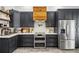 Modern kitchen featuring gray cabinets, stainless steel appliances, and a custom wood range hood at 2050 Jan Lan Blvd, St Cloud, FL 34772