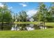 View of the backyard pond and the home's rear exterior with a blue sky and scattered clouds at 23647 Seneca Ridge Ct, Christmas, FL 32709
