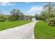 View of the house with a long concrete driveway, lush green lawn, and mature trees at 23647 Seneca Ridge Ct, Christmas, FL 32709