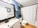 Blue bathroom with patterned shower curtain, stylish shelving, and a modern sink at 312 W Hull Ave, Oakland, FL 34760