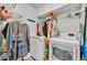 This is a laundry room with washer, dryer, storage shelves, and hanging clothes at 384 Old Alemany Pl, Oviedo, FL 32765