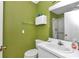 Green-walled bathroom featuring a white vanity, toilet, mirror, medicine cabinet and shower/tub combo at 40533 E 8Th Ave, Umatilla, FL 32784