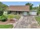 Inviting single-story home with a long driveway leading to a garage, surrounded by mature landscaping and a private yard at 40533 E 8Th Ave, Umatilla, FL 32784