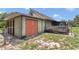 Exterior view of home with green siding, orange doors, and deck with outdoor storage shed at 40533 E 8Th Ave, Umatilla, FL 32784