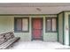 Covered front porch featuring a wooden bench, storm door and dark trim windows offering a welcoming entrance at 40533 E 8Th Ave, Umatilla, FL 32784