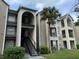 Three-story condo building features updated facade, black metal stairways, and a mature palm tree at 4756 Walden Cir # 21, Orlando, FL 32811