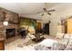 Living room with stone fireplace, tiled floors, ceiling fan, and tropical beach accent wall at 4933 Round Lake Rd, Apopka, FL 32712