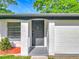 Charming home exterior with a gray front door, well-maintained yard, and attached garage at 514 S Cottage Hill Rd, Orlando, FL 32805