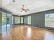 Bright main bedroom with tray ceilings, ceiling fan, wood floors, and sliding glass door to outdoor space at 5311 Saddleback Ct, Lady Lake, FL 32159
