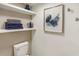 Bathroom view with floating shelves, neatly stacked towels, and decorative wall art above the toilet at 563 Midway Trak # K102, Ocala, FL 34472