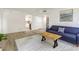 Living room showcasing wood-look floors, a blue sofa, and a view into the kitchen and hallway at 563 Midway Trak # K102, Ocala, FL 34472