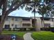 Apartment building featuring mature landscaping and a sidewalk leading to the entrance at 6108 Curry Ford Rd # 116, Orlando, FL 32822