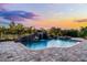 Backyard pool with rock waterfall feature, spa, and patio, set against a colorful sky at 9019 Tower Pine Dr, Winter Garden, FL 34787