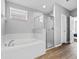Bathroom featuring an open shower with glass door, a soaking tub and wood look flooring at 903 Tramells Trl, Kissimmee, FL 34744