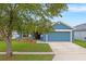 Charming blue single-story home with green lawn, complemented by mature trees for added shade at 903 Tramells Trl, Kissimmee, FL 34744