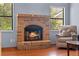 Living room fireplace with red brick, windows, and an adjacent easy chair at 1032 Silcox Branch Cir, Oviedo, FL 32765