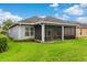 View of the back of the home, showing the screened lanai and lush, green lawn at 1035 Stoney Creek Dr, Lakeland, FL 33811