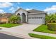 Inviting single-Gathering home showcasing a well-kept lawn, tropical trees, and an attached two-car garage at 1035 Stoney Creek Dr, Lakeland, FL 33811