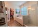 Bright bathroom features a glass enclosed shower, soaking tub, and walk-in closet access at 13940 Magnolia Ridge Loop, Winter Garden, FL 34787