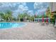 Beautiful community pool with sun loungers, tables, and umbrellas under a partly cloudy blue sky at 13940 Magnolia Ridge Loop, Winter Garden, FL 34787