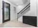 Bright foyer featuring a modern black door, staircase, wood-look flooring, and a cabinet for organized storage at 14215 Lakeview Park Rd, Winter Garden, FL 34787