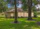 The backyard features mature trees, lush green grass, and a covered screened-in lanai at 1701 Lucky Pennie Way, Apopka, FL 32712