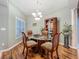 Dining room with a glass table, four chairs, light fixture and a decorative shelving unit, and hardwood floors at 1701 Lucky Pennie Way, Apopka, FL 32712