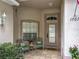 Cozy front porch features comfortable seating and decorative plants, next to the home's front door and large window at 1701 Lucky Pennie Way, Apopka, FL 32712