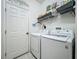 Bright laundry room with modern appliances and upper shelving for organized storage solutions at 1701 Lucky Pennie Way, Apopka, FL 32712