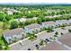 This aerial view shows a residential community with lush landscaping, several townhome buildings, and beautiful blue skies at 17441 Hidden Forest Dr, Clermont, FL 34714