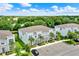 This aerial view shows a townhome community with white townhomes, palm trees, and a lush green landscape at 17441 Hidden Forest Dr, Clermont, FL 34714
