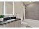 This bathroom features a large vanity with a black countertop, a tub shower combo with grey tile, and a lighted mirror at 17441 Hidden Forest Dr, Clermont, FL 34714