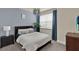 This is a blue bedroom featuring a queen bed, a nightstand with a lamp, blue curtains, and a silver light fixture at 17441 Hidden Forest Dr, Clermont, FL 34714