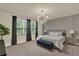 Cozy bedroom with a gray upholstered bed, custom lighting, and large windows at 17441 Hidden Forest Dr, Clermont, FL 34714