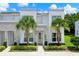 Contemporary townhome featuring a sleek white facade, stone accents, and lush landscaping at 17441 Hidden Forest Dr, Clermont, FL 34714
