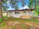 Back view of a block construction shed with a red roof and overgrown foliage at 1826 W Silver Springs Blvd, Ocala, FL 34475