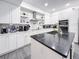 Bright kitchen featuring white cabinets, stainless appliances, a black island, and a marble backsplash at 224 Hammock Dunes Pl, Orlando, FL 32828